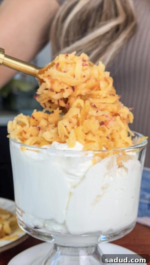 Frozen shaved peaches over creamy yogurt with a golden, crunchy oat crisp topping, served in a glass dessert cup.