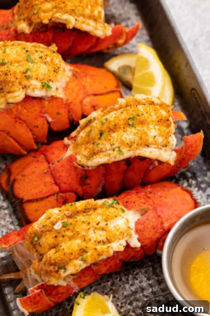 Four bright red lobster tails cooked in an Instant Pot then butterflied and set on a baking sheet, ready to be served.