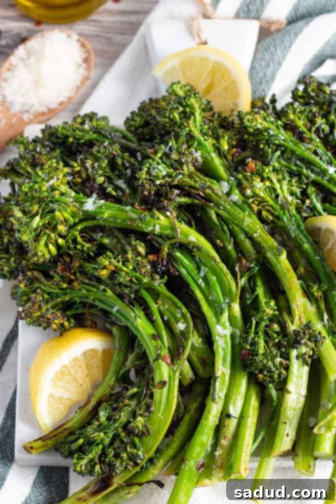 Overhead view of grilled broccolini on a platter with lemon wedges.