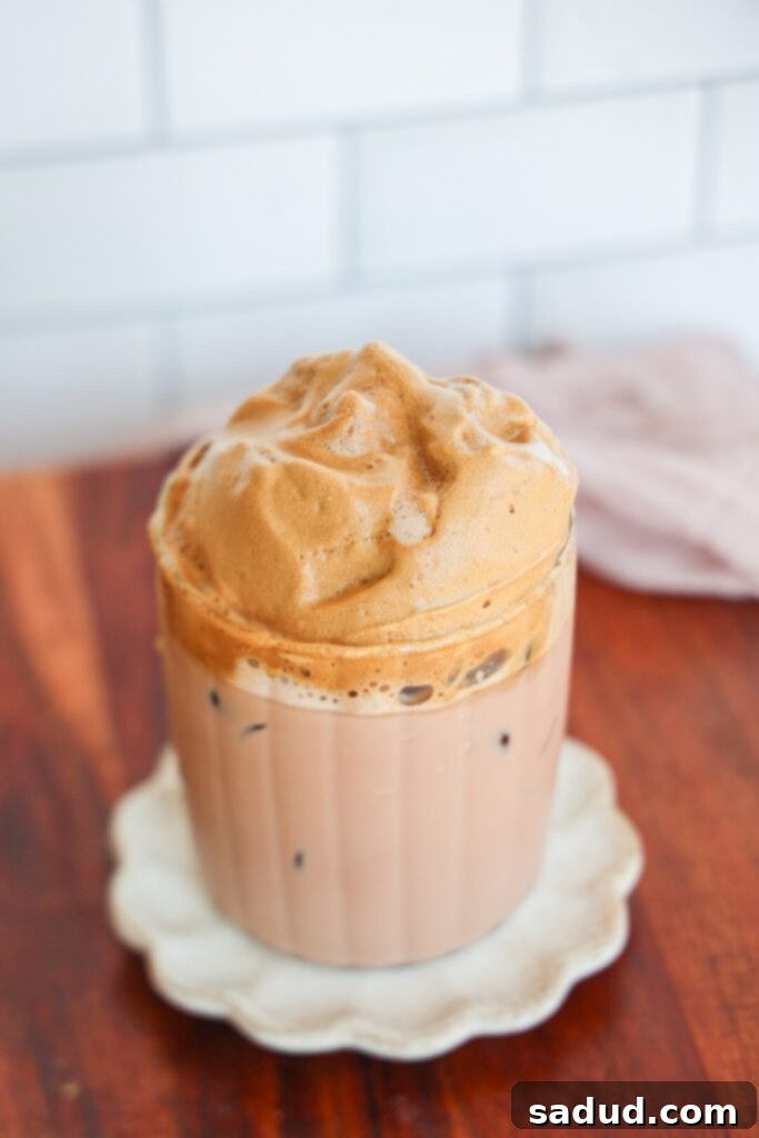 Close-up of a layered chocolate dalgona coffee, showing the rich chocolate milk base and the fluffy coffee foam on top.