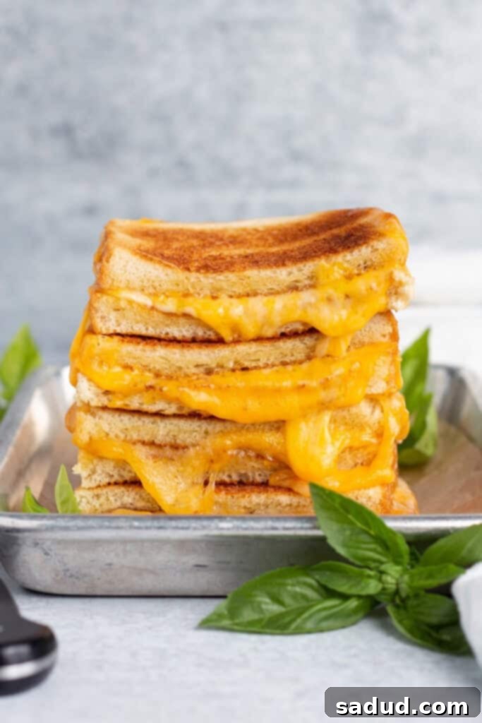 Zoomed out view of the side of a stack of toasted grilled cheese halves on a sheet pan.