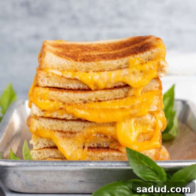 Zoomed out view of the side of a stack of toasted grilled cheese halves on a sheet pan.