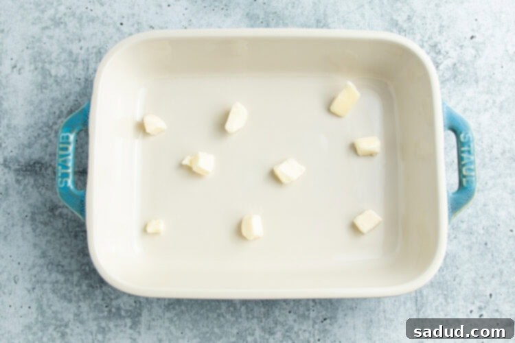 Overhead view of a 9x13 baking dish with pieces of butter distributed throughout the bottom.