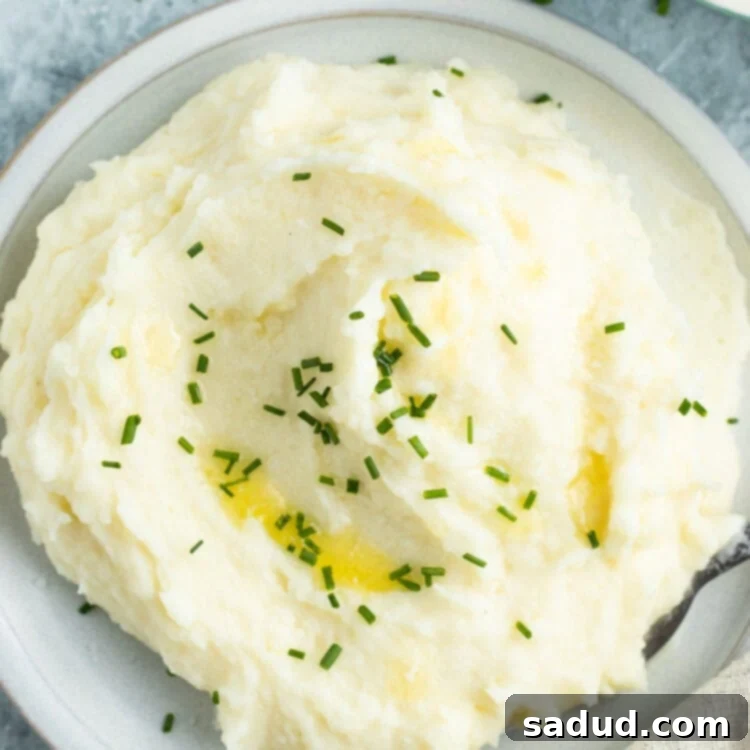 Overhead view of a pile of potato mousseline on a white plate next to a casserole dish of potatoes, showcasing its smooth, creamy texture.