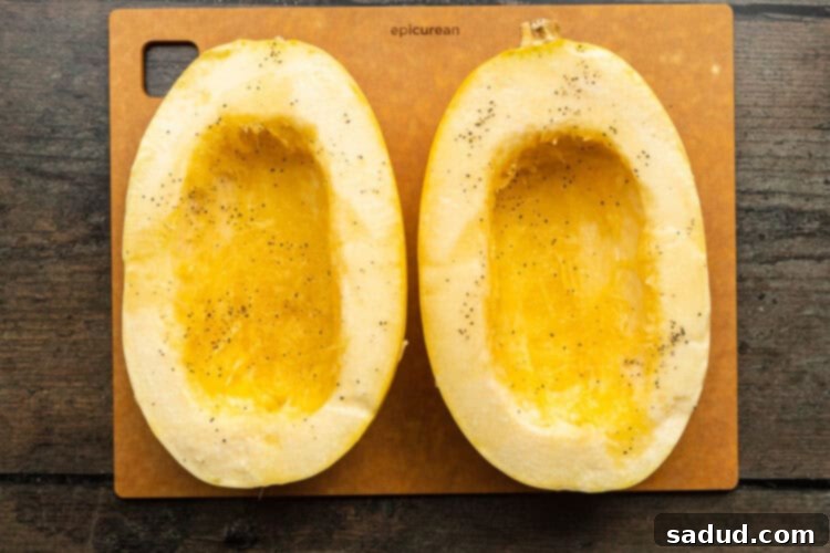 Overhead view of 2 halves of a spaghetti squash on a cutting board, seasoned and ready for the grill.