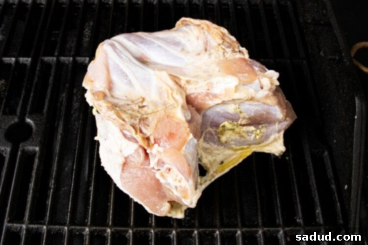 Brined and buttered turkey breast resting directly on a gas grill grate over indirect heat, cooking slowly to perfection.