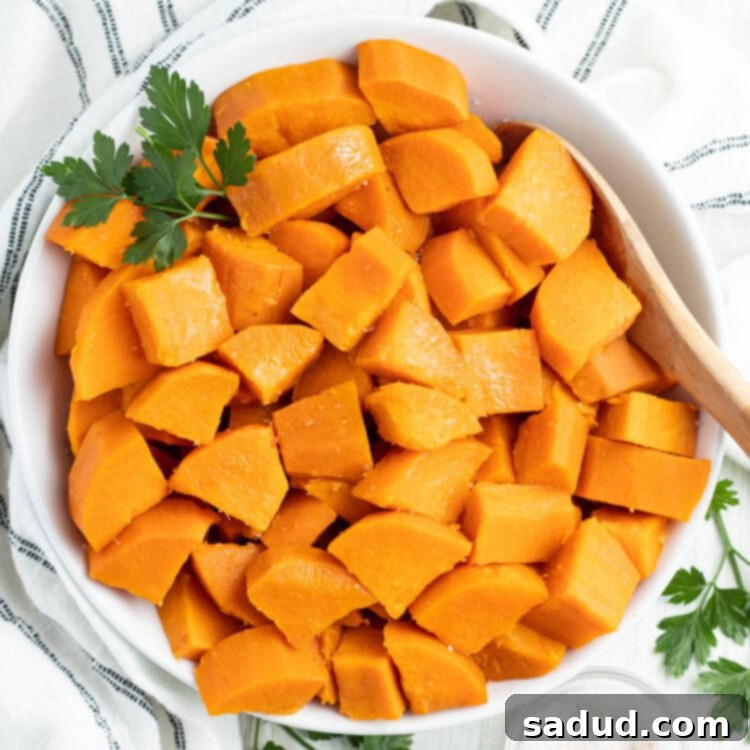 The Best Way to Boil Sweet Potatoes 4 Overhead view of a large white bowl of cubed, boiled sweet potatoes on a table with a white tablecloth.