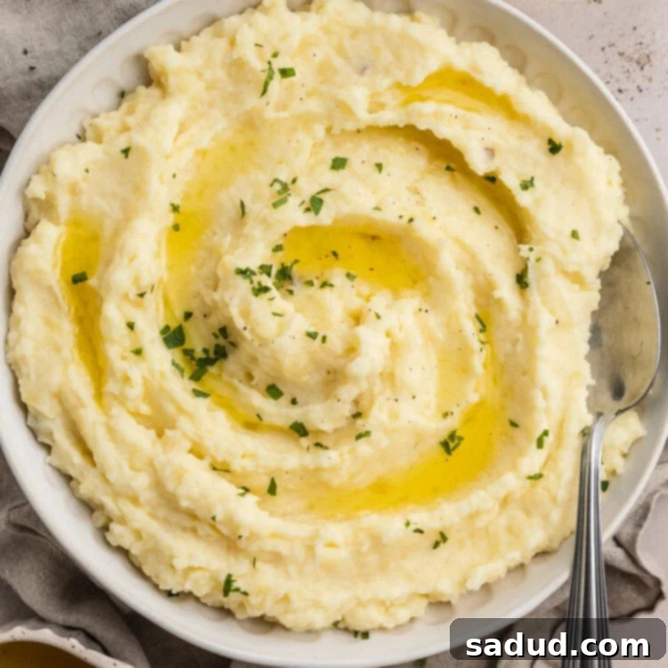 Overhead, zoomed out view of a large bowl of truffle mashed potatoes on a table set for the holidays.