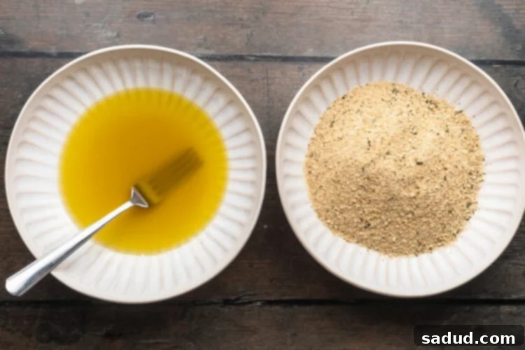Overhead view of two shallow bowls, one containing an egg and oil wash and the other breadcrumbs.