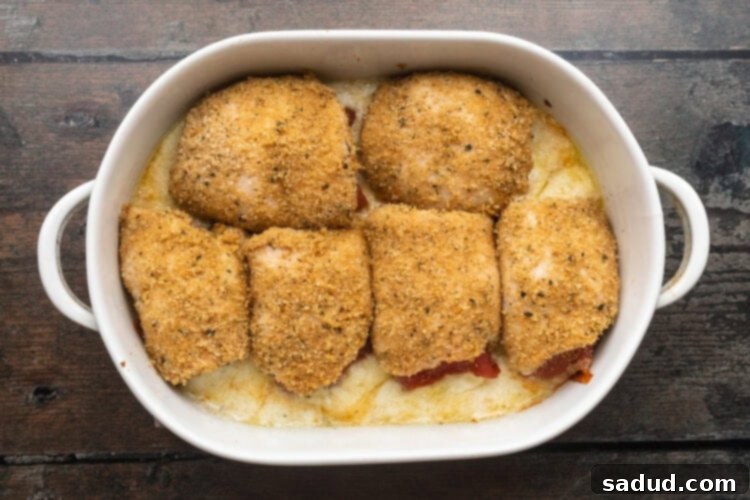 Baked chicken rollatini in a large white oval baking dish on a wooden table.