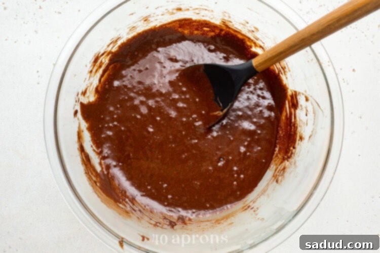 Dairy-free brownie batter with chocolate chips folded in, sitting in a large glass mixing bowl with a silicone spatula.