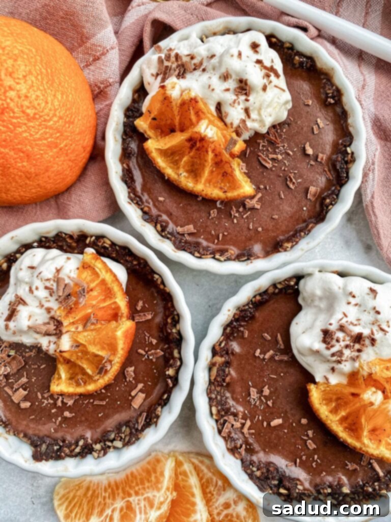 Three small chocolate ganache tarts topped with whipped cream and a candied Sumo Citrus slice.