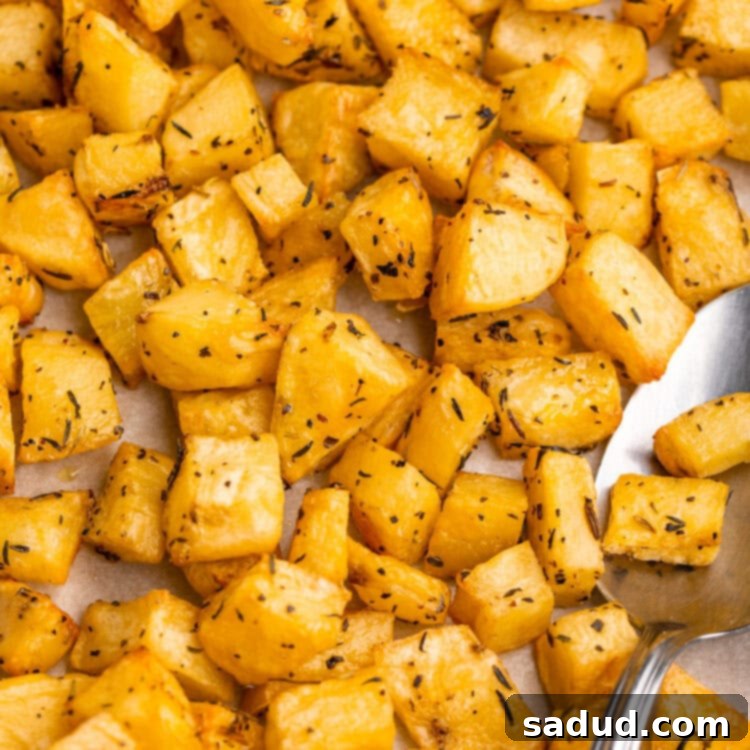 Close-up overhead view of the finished oven-roasted diced potatoes, golden brown and crispy, on a baking sheet with parchment paper.