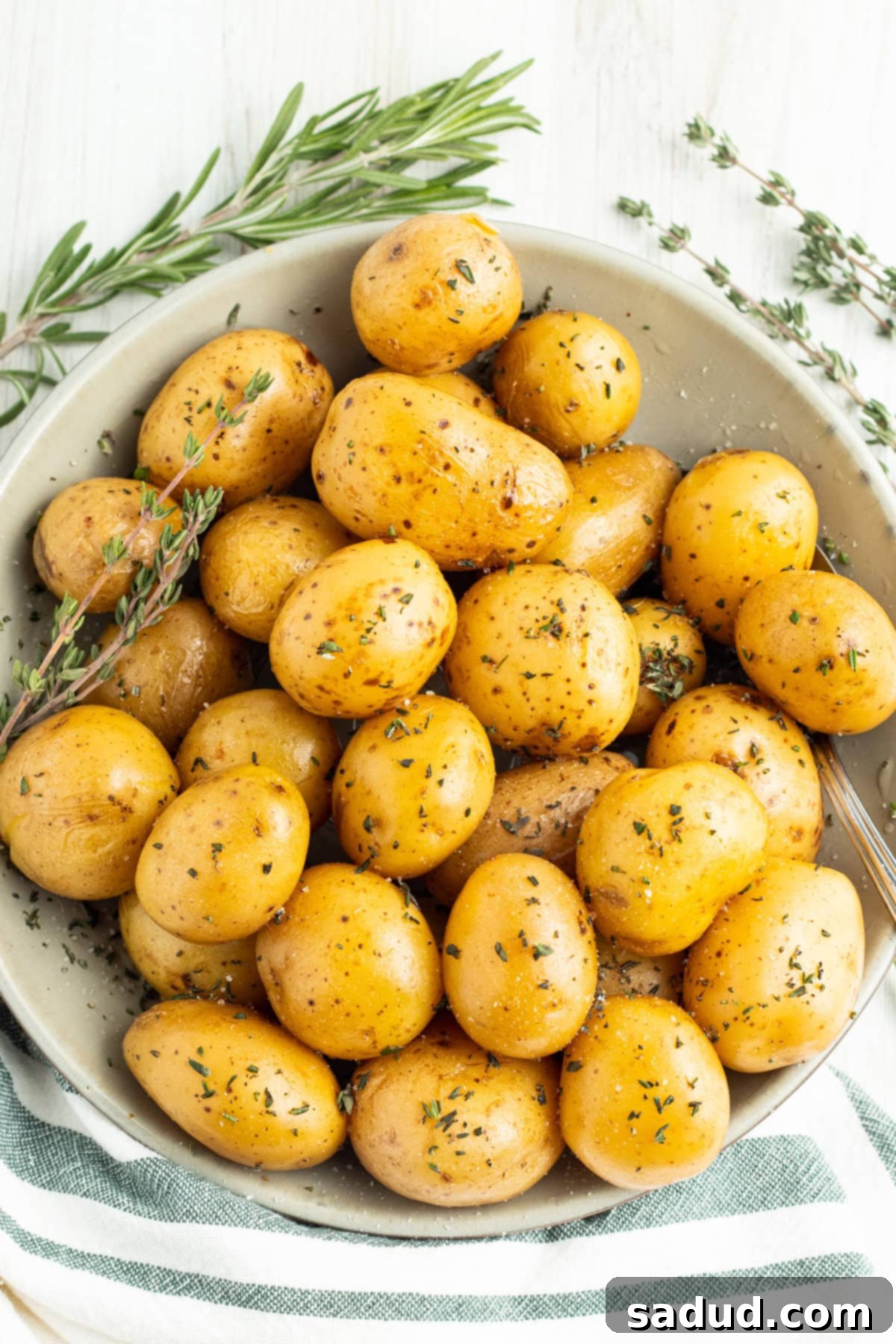 Overhead view of confit potatoes in a large serving bowl on a white tablecloth, ready to be enjoyed.