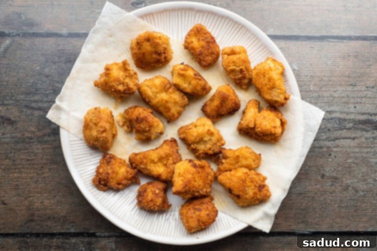 Overhead view of fried keto chicken nuggets on a plate lined with paper towels.