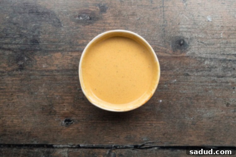 Overhead view of prepared keto Chick-fil-A sauce in a small bowl on a wooden table.