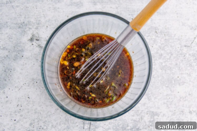 Air fryer tuna steak marinade in a glass mixing bowl with a whisk.