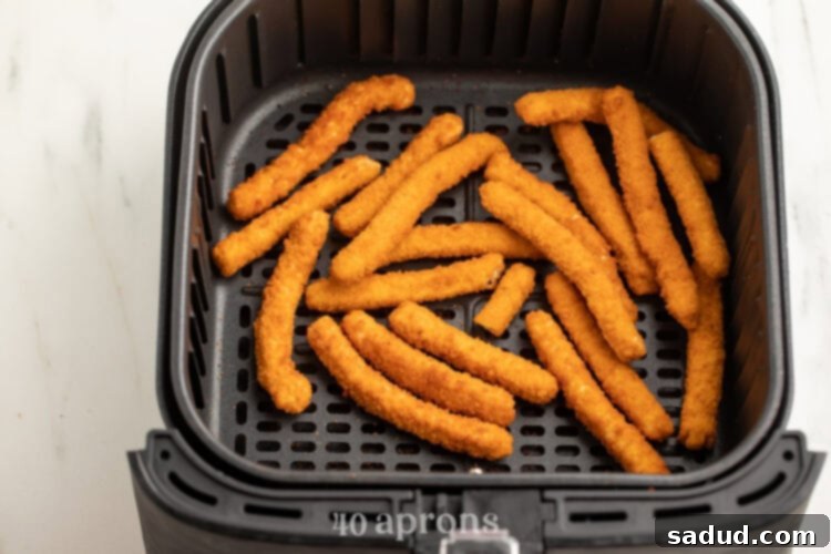 Frozen chicken fries in an air fryer basket.