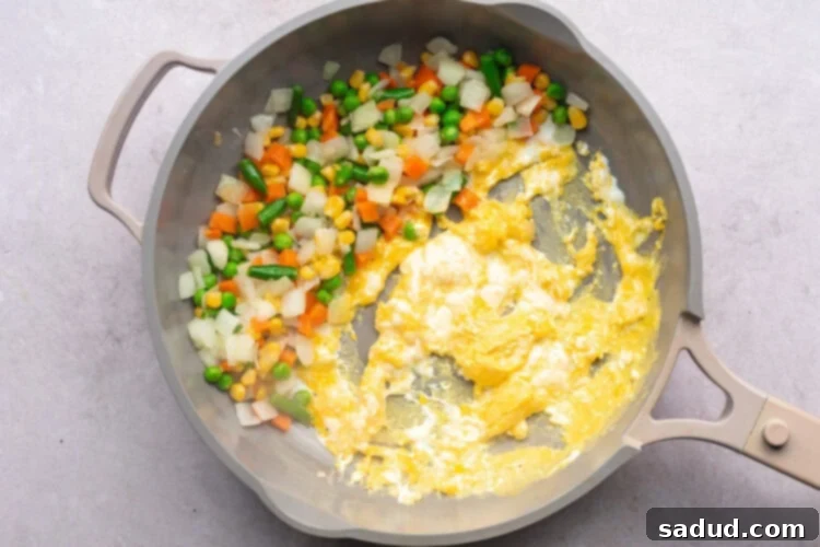 Mixed veggies and scrambled eggs in a large skillet.