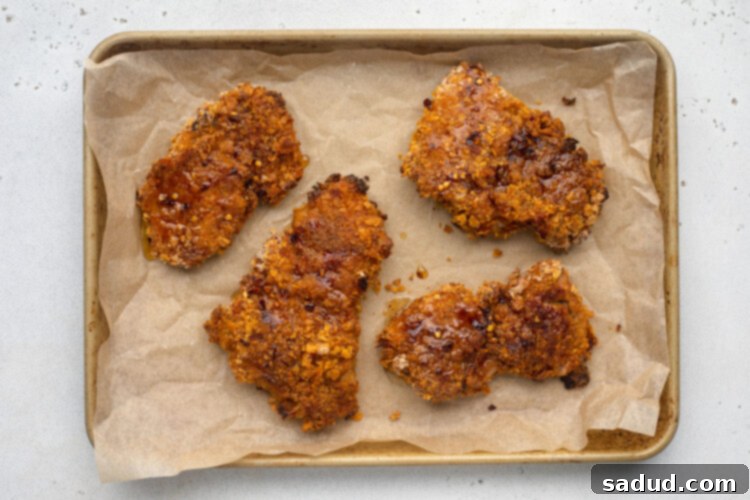 Hot honey chicken on a baking sheet lined with parchment paper.