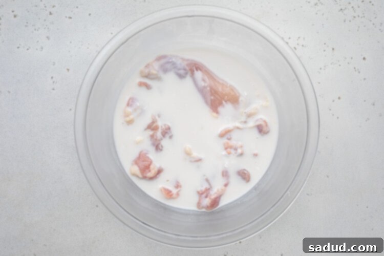 Chicken submerged in a buttermilk mixture.