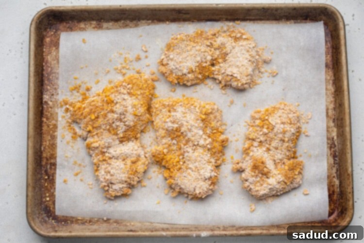 Breaded hot honey chicken on a baking sheet lined with parchment paper.