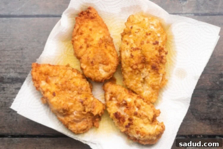 Fried chicken on a wire rack over paper towels, ready to rest.