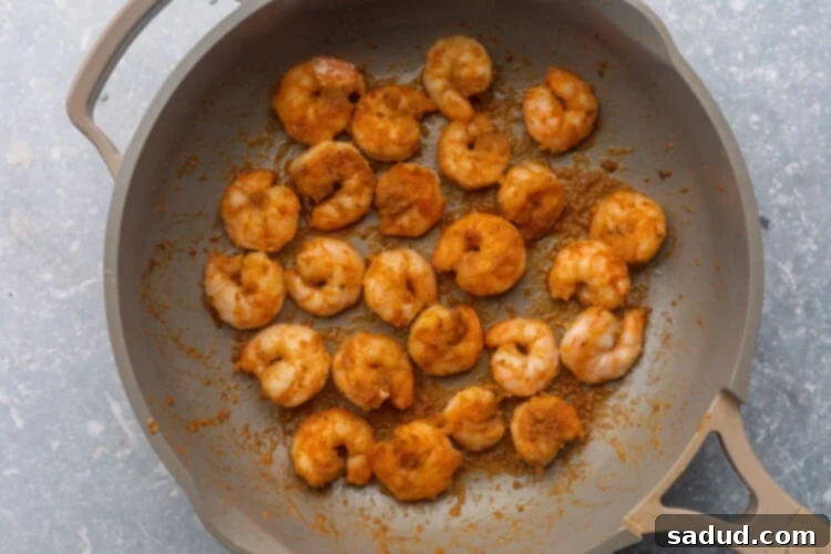 Seasoned, sautéed shrimp in a large skillet, perfectly cooked.