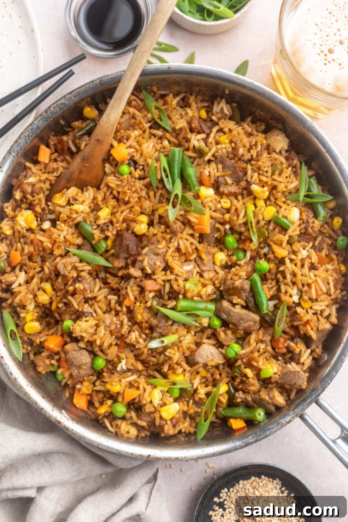 Crispy Duck Fried Rice 2 Overhead view of a large silver skillet of duck fried rice with veggies.