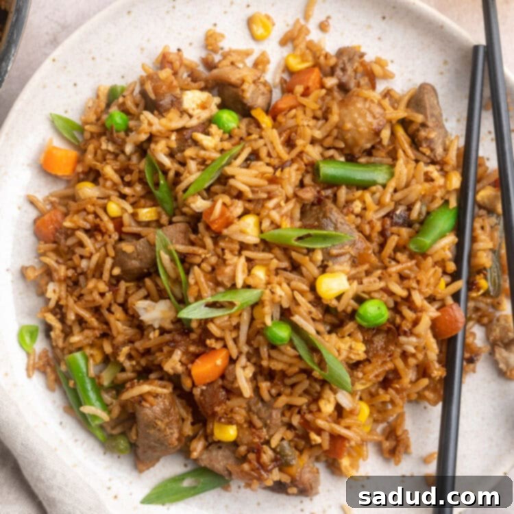 Crispy Duck Fried Rice 4 Overhead view of a large white plate of duck fried rice with veggies.