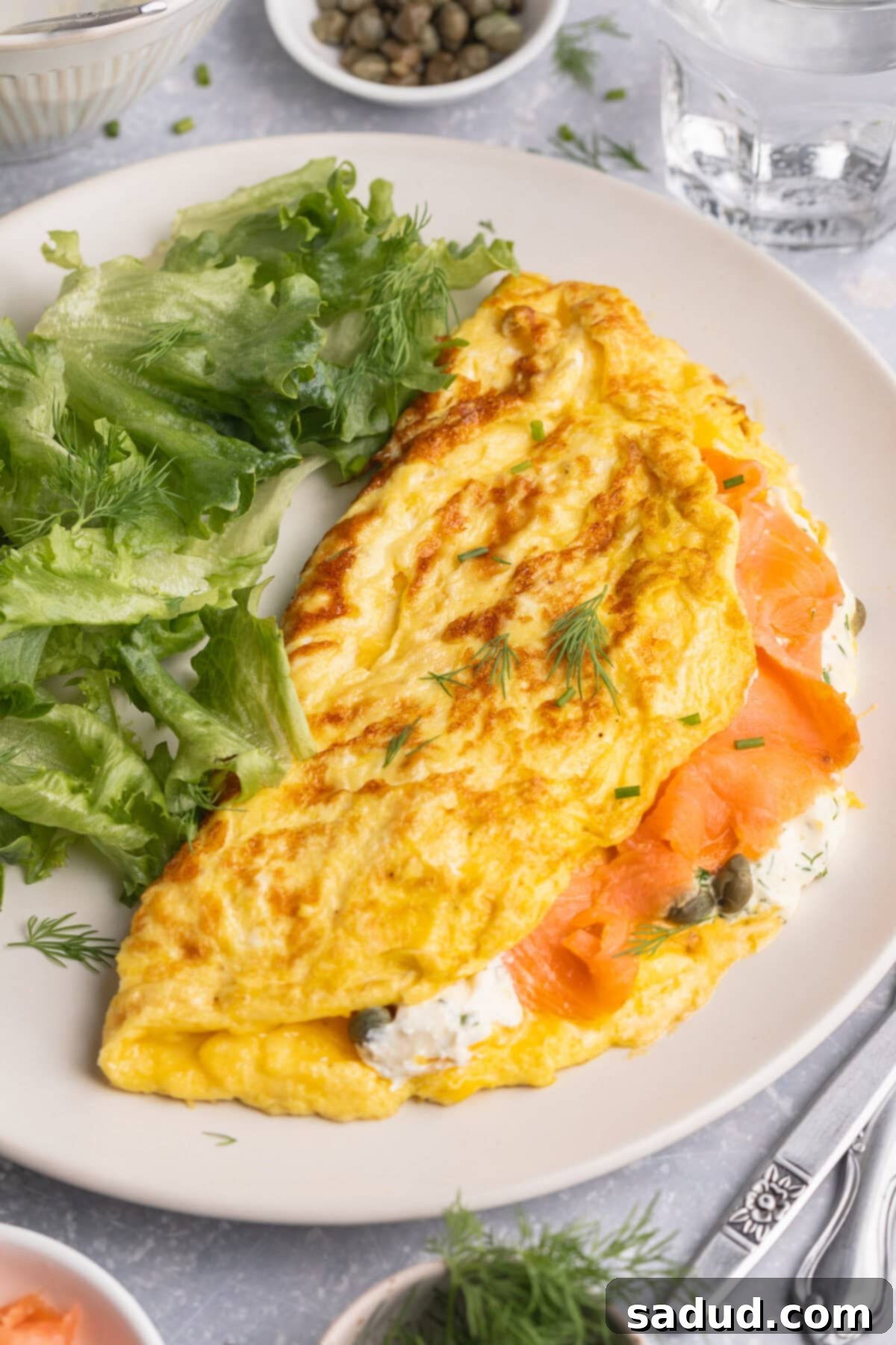 Overhead view of a folded salmon omelette on a plate with a green salad.