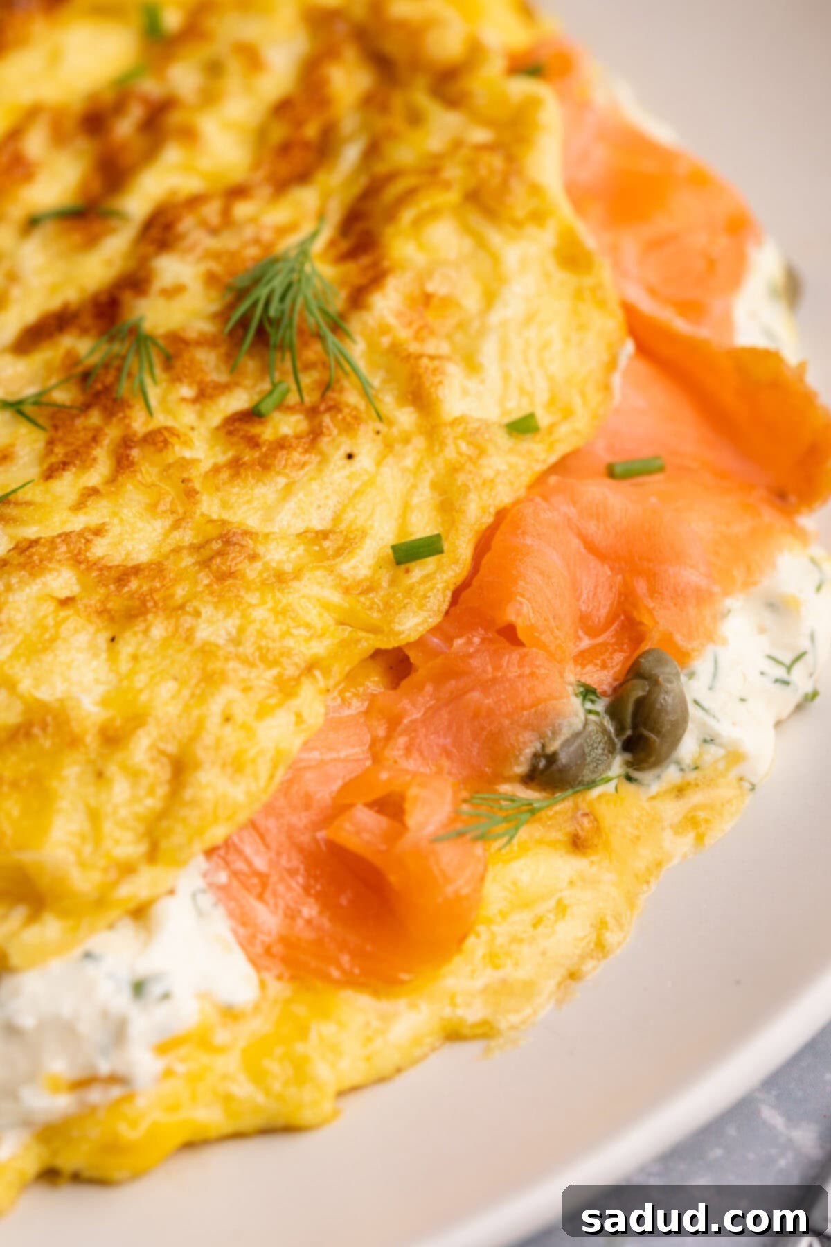 Close-up view of a folded salmon omelette on a plate with a green salad.