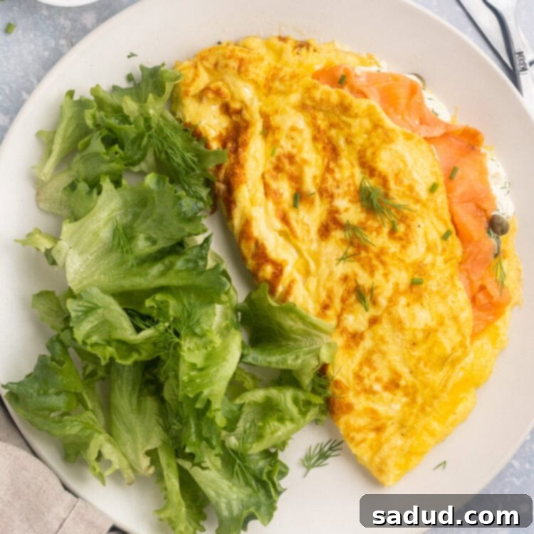 Overhead view of a folded salmon omelette on a plate with a green salad.