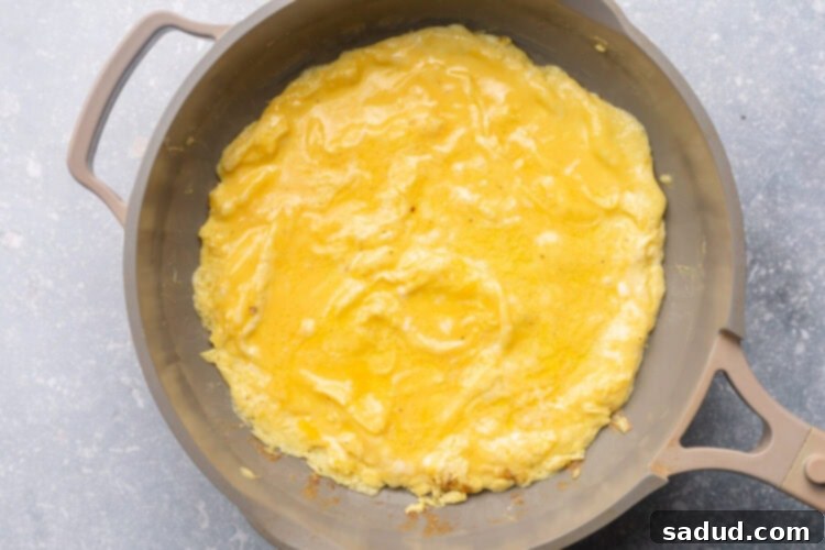 Scrambled eggs for salmon omelette in a large skillet.
