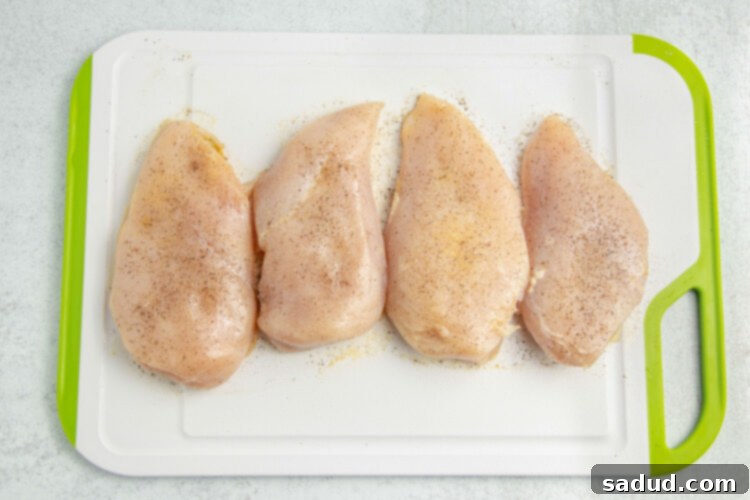 Seasoned chicken breasts on a cutting board.