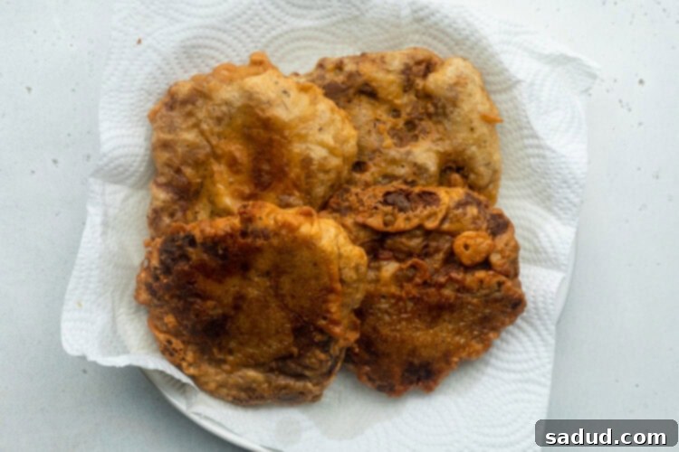 Battered and fried seitan fillets for vegan chicken sandwiches, resting on a plate lined with paper towels.
