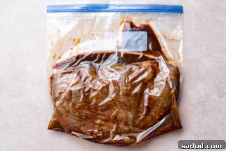 Cooked sous vide flank steak still in its large ziploc bag with remaining marinade, ready for searing.