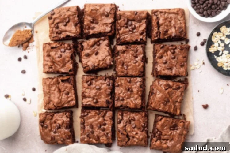 16 fully-baked lactation brownies sliced into squares on a sheet of parchment paper.