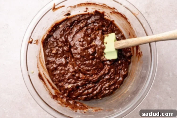 Prepared lactation brownie batter in a large glass mixing bowl with a silicone spatula.
