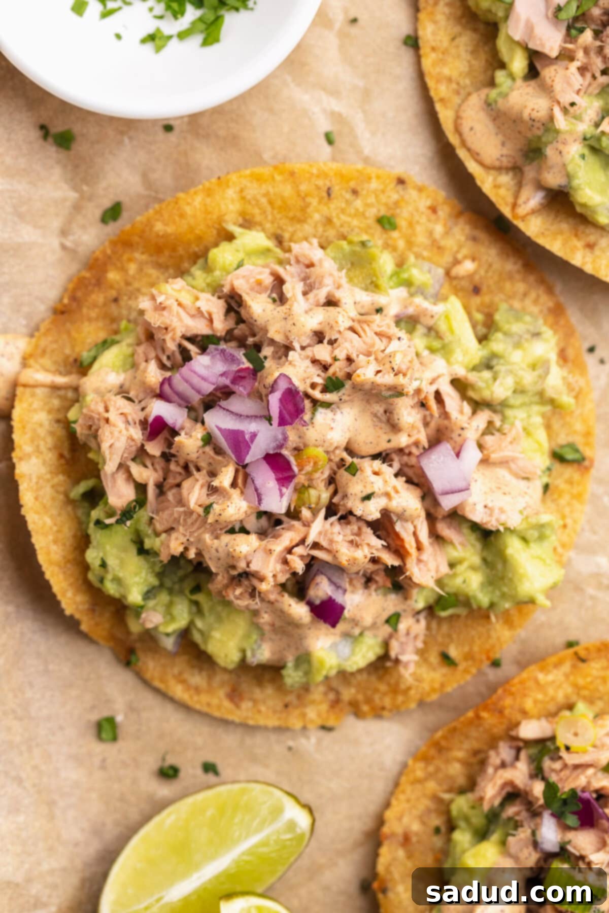 Top-down view of a cirspy corn tostada topped with tuna, guac, slaw, and other fresh ingredients.