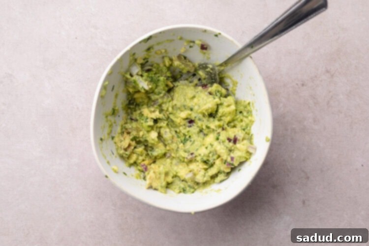 Quick guacamole for tuna tostadas in a medium mixing bowl with a fork.