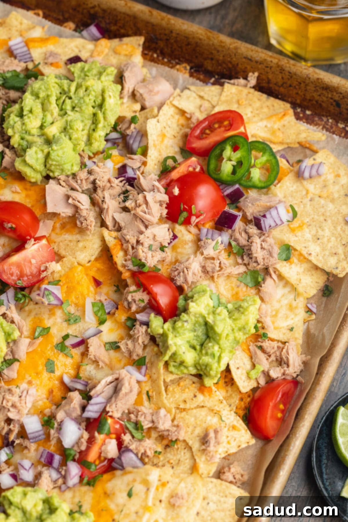 Effortless Tuna Nacho Feast 2 Overhead view of tuna nachos with various nacho toppings spread out across a baking sheet.