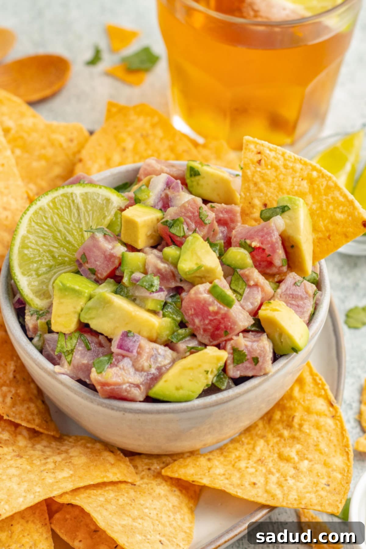 Zesty Tuna Ceviche 2 Side view of a bowl of tuna ceviche with chunks of ahi tuna, avocado, cilantro, and red onion with tortilla chips.