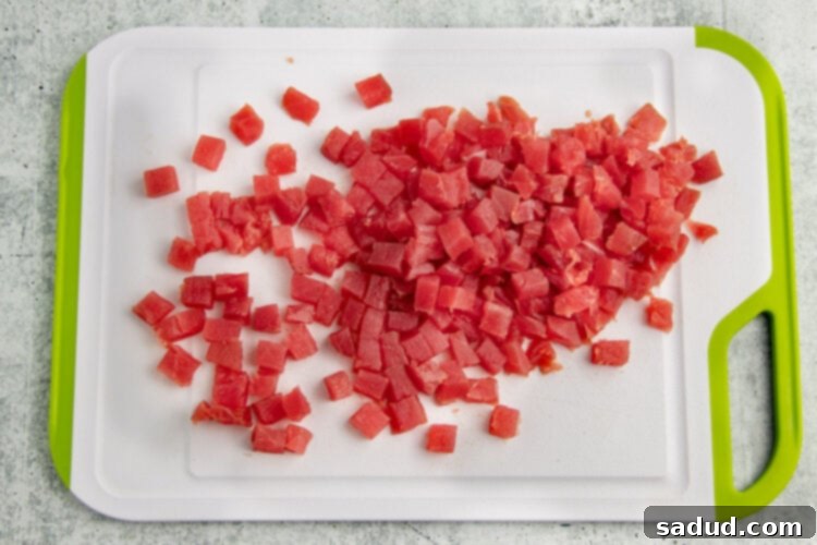 Chunks of ahi tuna on a plastic cutting board with lime green edges.