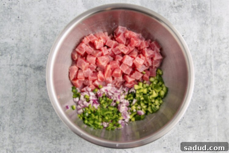 Ingredients for tuna ceviche in a large silver mixing bowl.