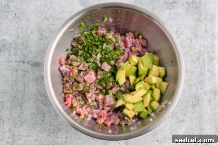Ingredients for tuna ceviche in a large silver mixing bowl.