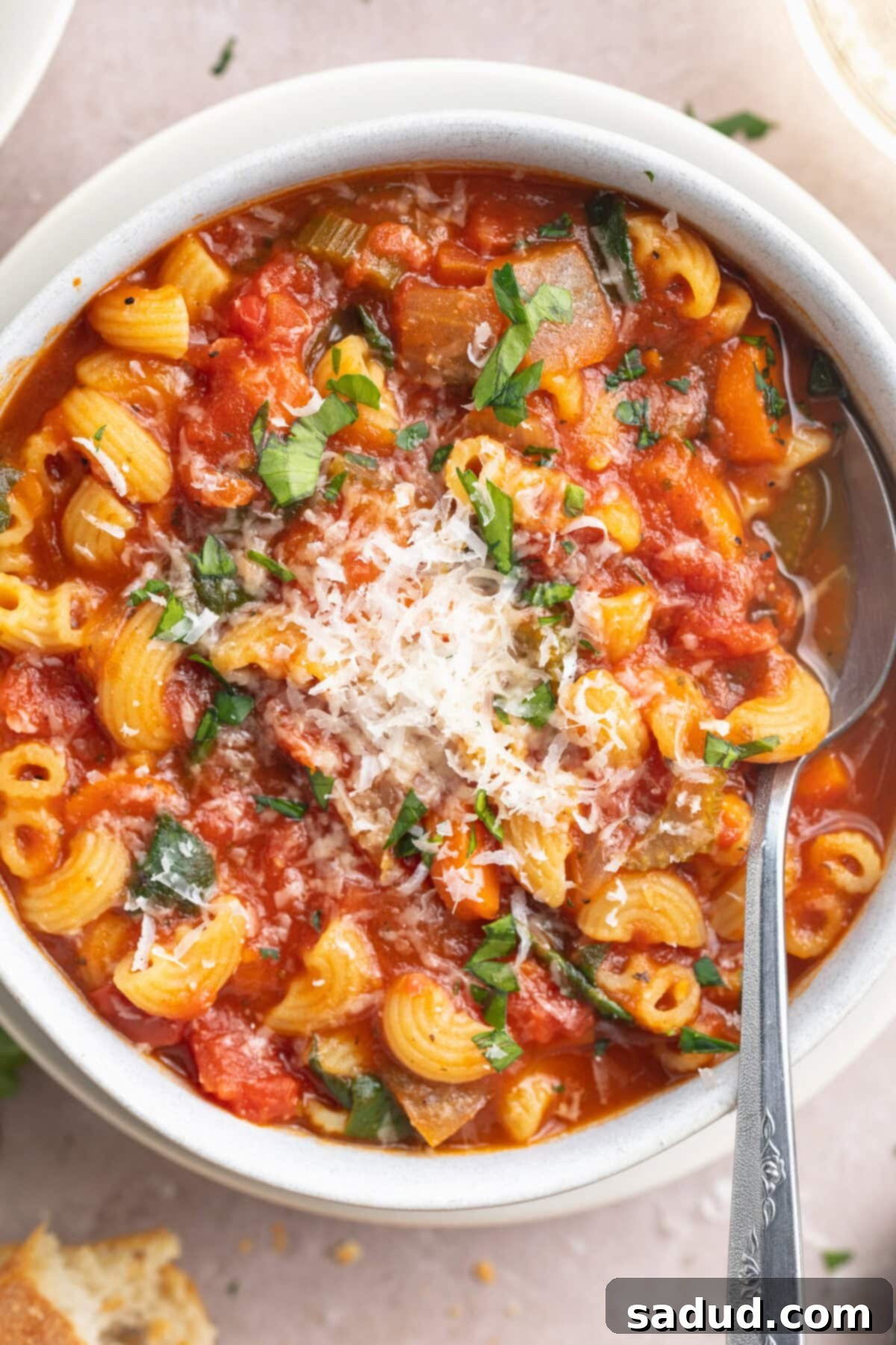 Close-up of a steaming bowl of tomato florentine soup, with visible spinach and macaroni, ready to be enjoyed.