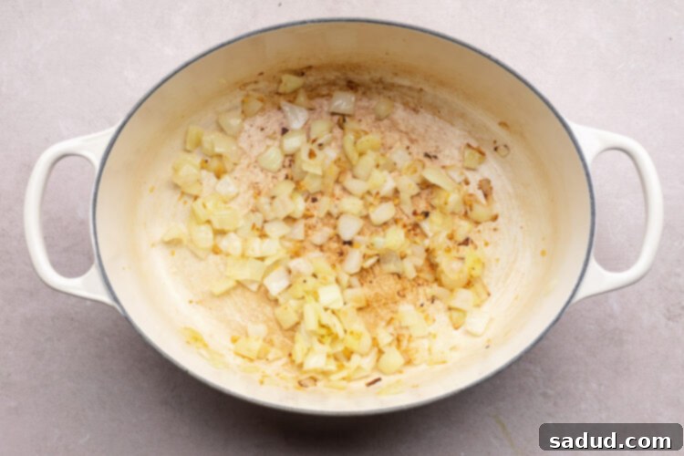 Diced onion and garlic in a large oval dutch oven with 2 handles.