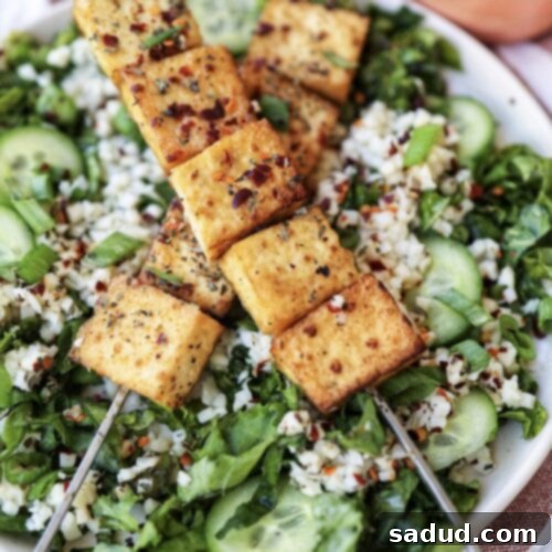 A vibrant salad topped with crispy tofu satay and creamy peanut sauce, ready to be enjoyed.