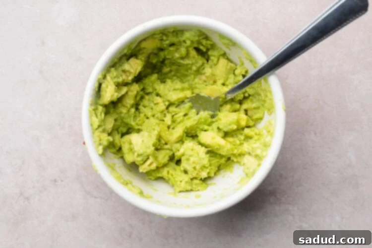 Guacamole in small white mixing bowl with a fork.